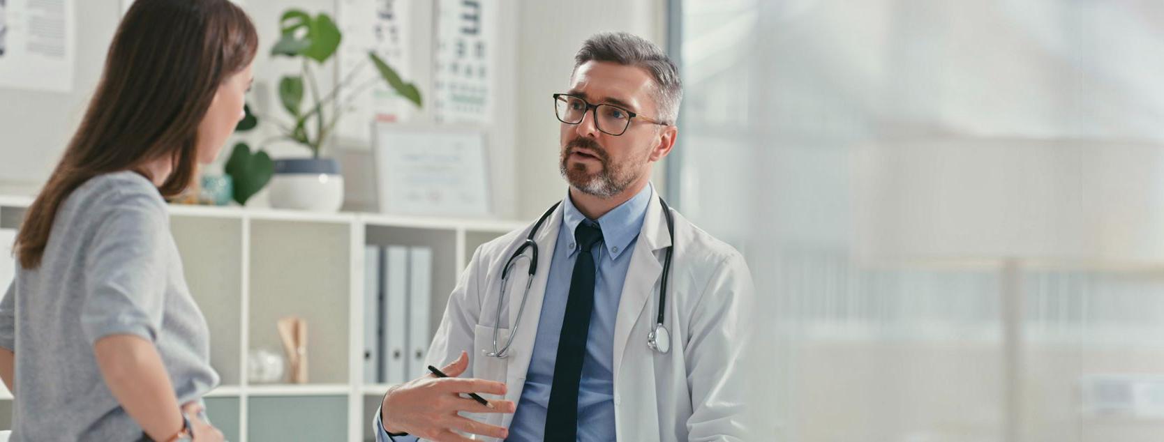 A doctor speaks to his female patient at an appointment.